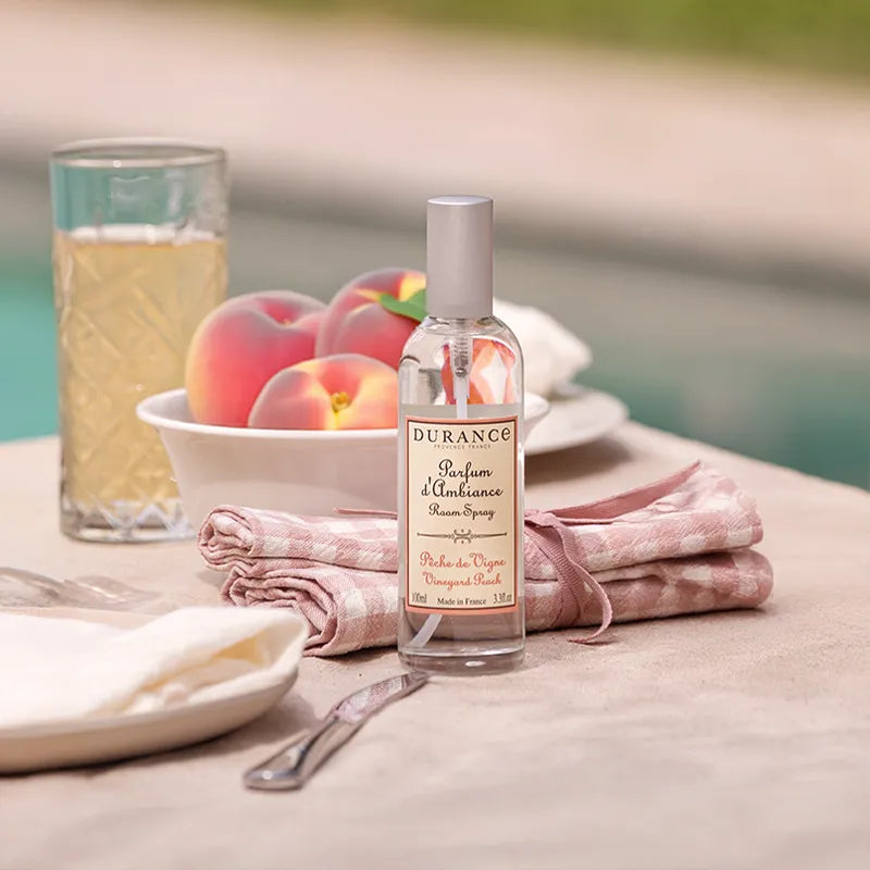 Bottle of Durance Air Freshener on a table with peaches and a glass of juice.
