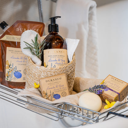 Bath products including bottles, soap, and a towel in a basket on a bathtub.Lavender & Broom Soap 