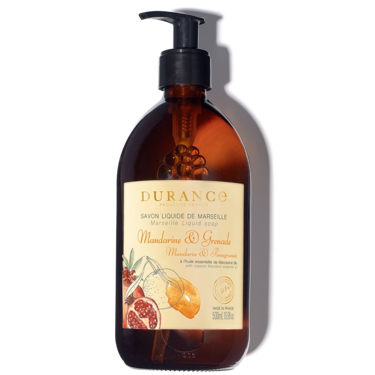 A clear pump bottle with brown liquid, labeled 'Durance', 'Savon liquide de Marseille', 'Mandarin & Pomegranate' with images of mandarin oranges and pomegranate fruits.