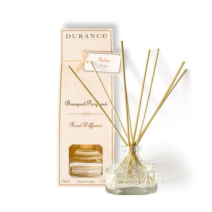 A Durance branded amber scented oil diffuser with a clear glass bottle and gold-colored amber oil, placed next to its packaging box.