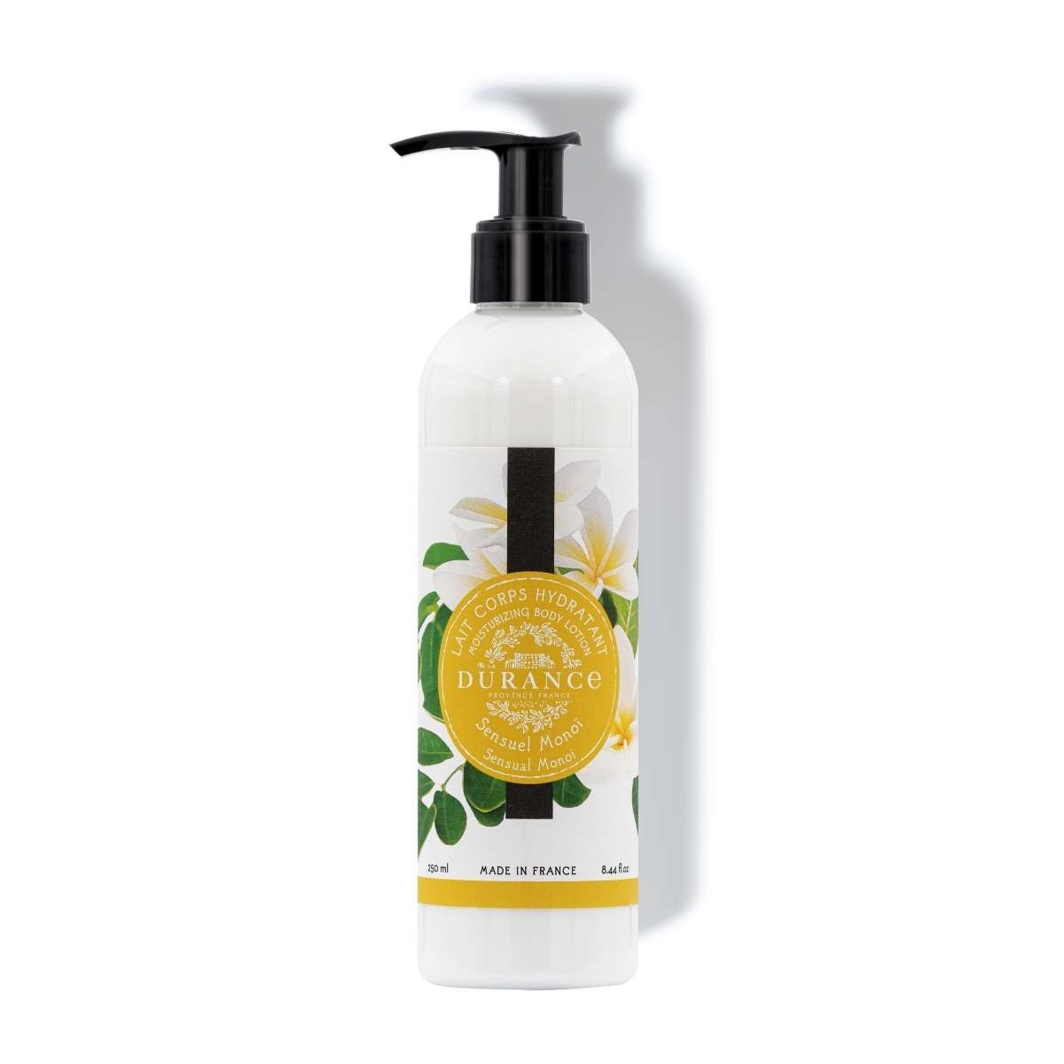 A white pump bottle with a label that has the brand 'Durance' and the product name 'Sensual Monoi'. There are images of flowers and leaves, and the text indicates the product is a moisturizing body lotion.