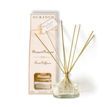 A Durance brand scented bouquet Silver Cedar Diffuser 100 ml with several gold-colored sticks, a clear glass vase, and a pink cardboard packaging box with the product name and weight information.